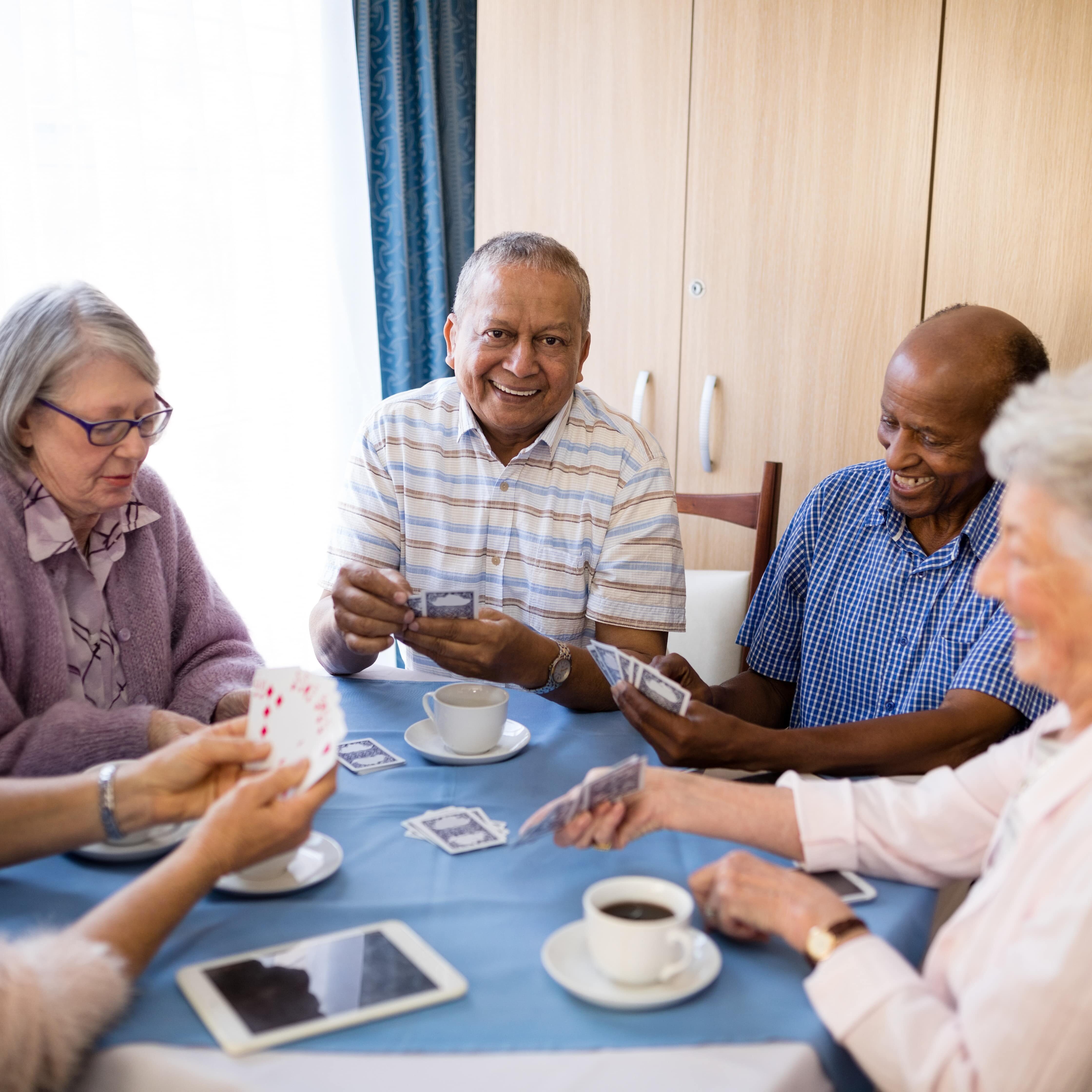 Multi-ethnic senior friends playing cards at table