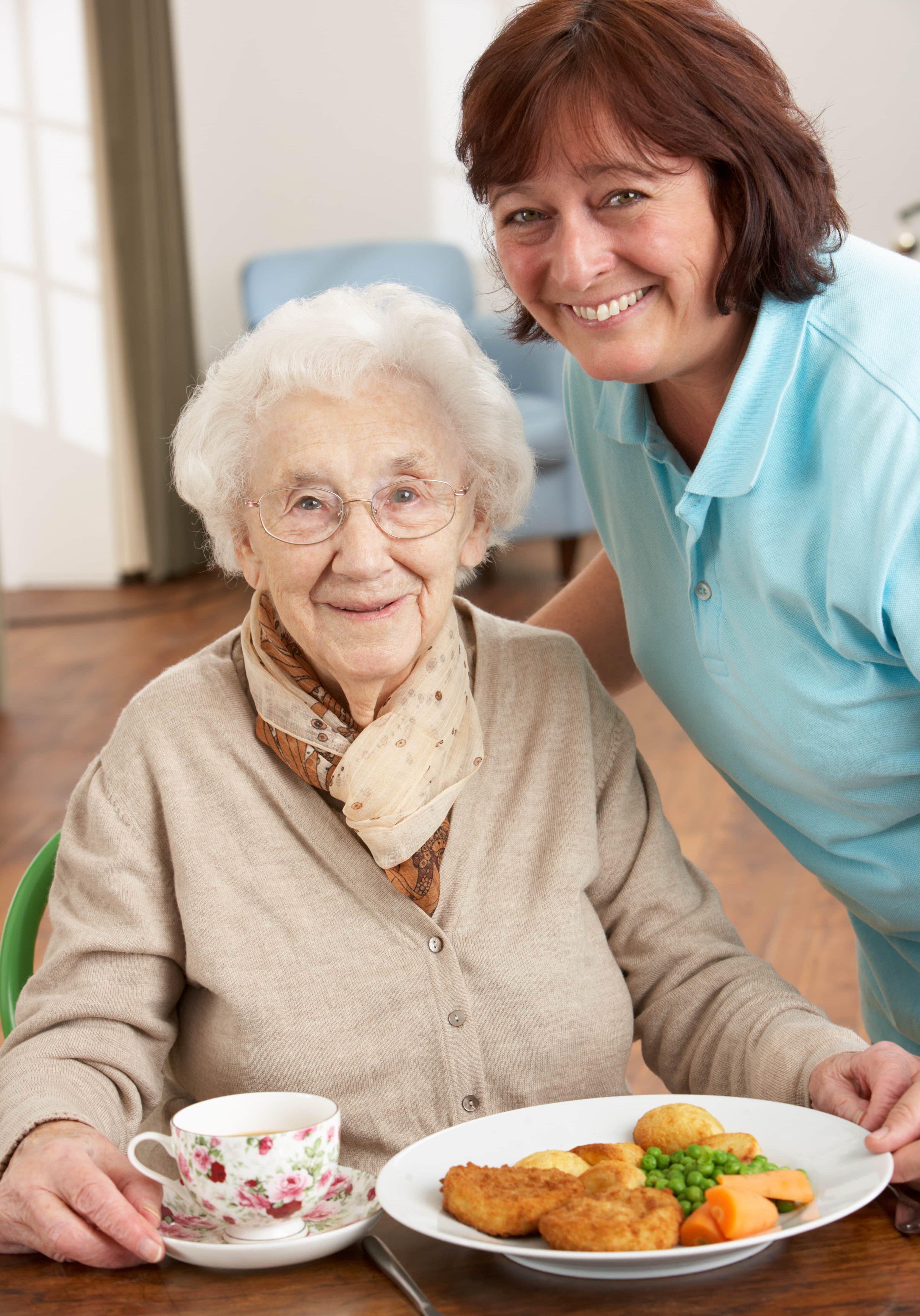 Senior woman being served meal by caregiver